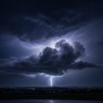 Foto kilatan petir menyambar dari awan badai yang gelap dan tebal saat malam hari.