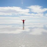 Dataran garam Salar de Uyuni memantulkan langit biru dengan awan sempurna saat musim hujan, menciptakan ilusi optik.