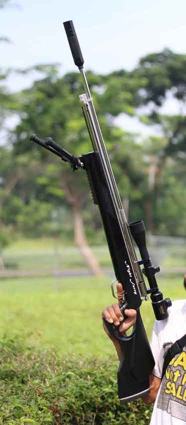 Seseorang memegang senapan angin modern dengan teleskop dan peredam.